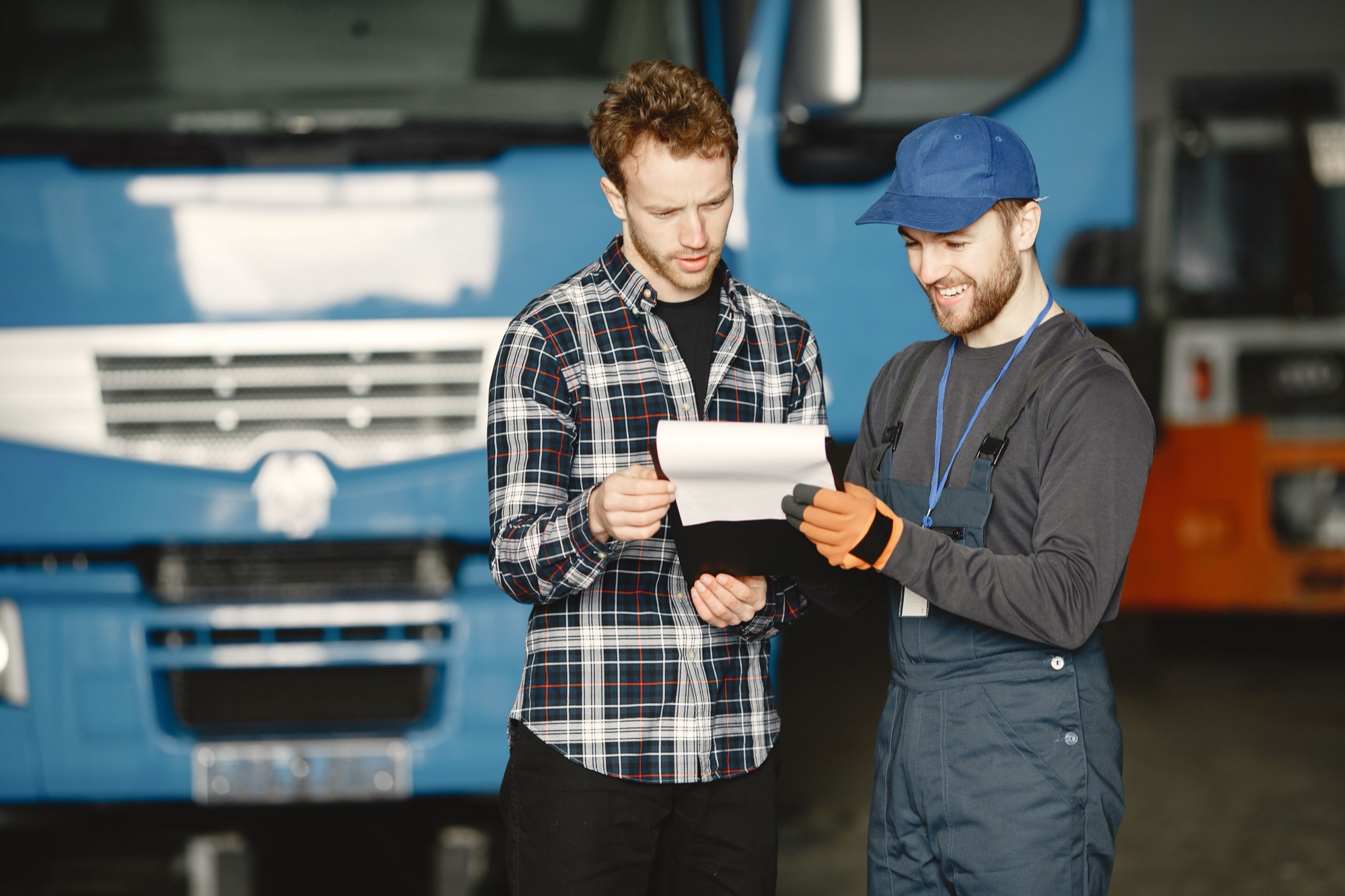 Fleet owner and driver reviewing paperwork in front of a blue truck